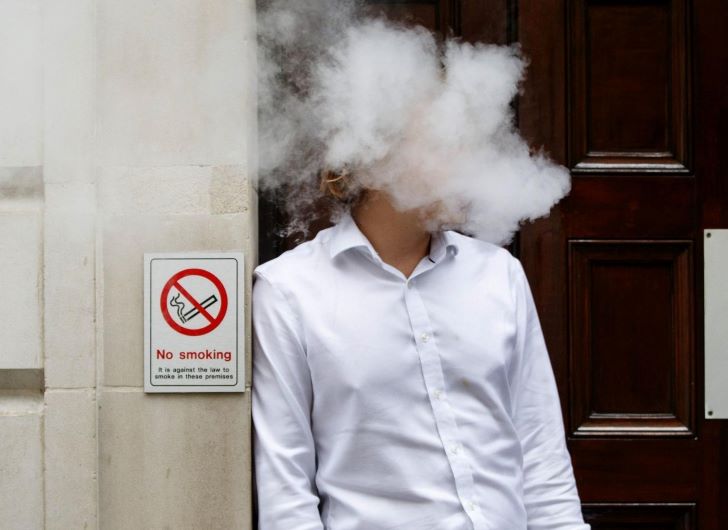 Merokok di bawah tanda larangan merokok (Foto: Health News Florida)