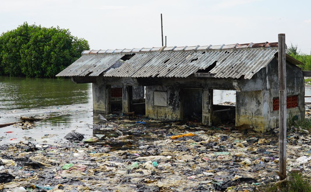Dulu bangunan ini WC umum. Kini bukan hanya tak bisa digunakan, tapi tak pernah surut dari rob yang membawa sampah dari hilir Kanal Banjir Timur. (Foto: Aldhila Putra Wedaswara)