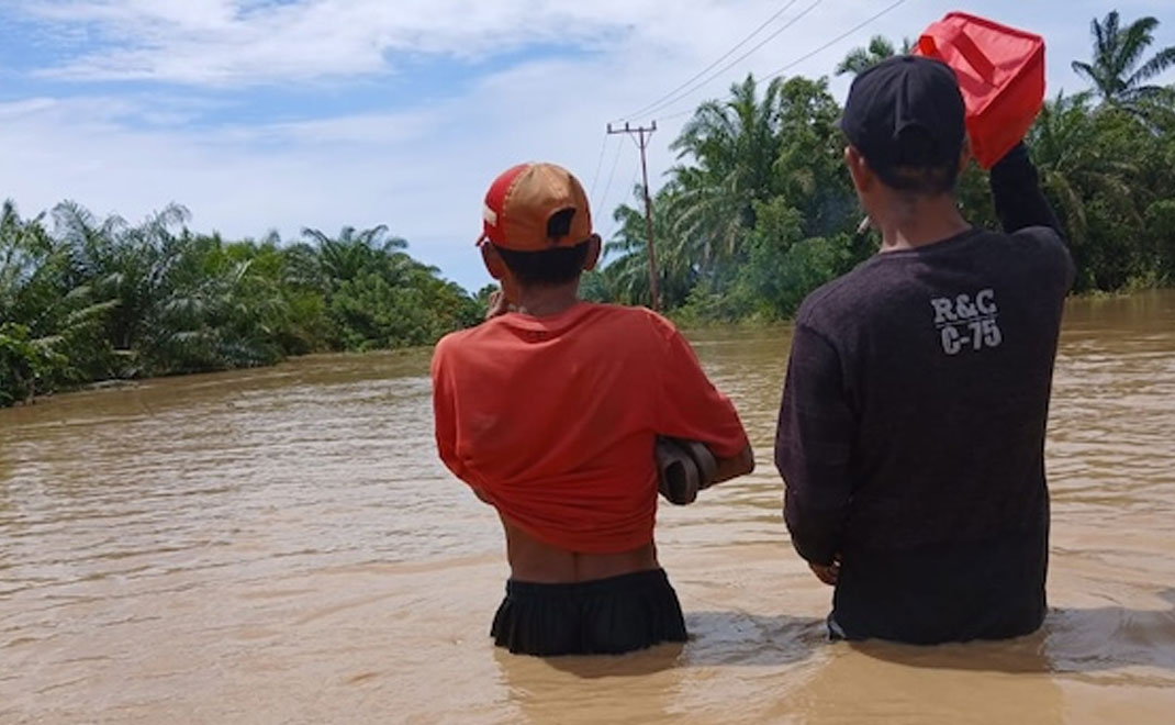 Dua sukarelawan menerjang banjir setinggi pinggang orang dewasa di Desa Alue Siron, Kecamatan Tadu Raya, Kabupaten Nagan Raya, Provinsi Aceh pada 28 November 2025. (Dokumentasi Apel Green Aceh)